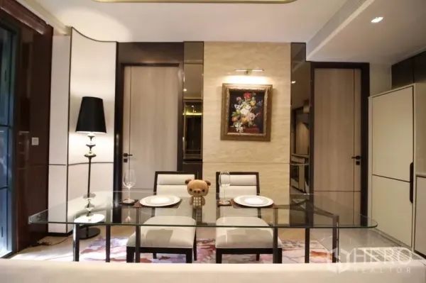 Condominium for rent in Watthana, Bangkok - Close-up of dining space featuring a glass table, upholstered chairs and wall art under soft lighting.