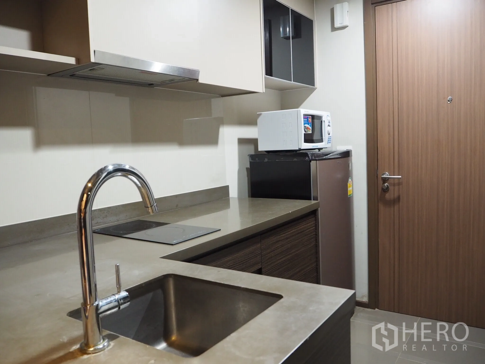 Condominium for rent in Phaya Thai, Bangkok - Compact modern kitchenette with stainless sink, electric cooktop, microwave and fridge in Phaya Thai condo.
