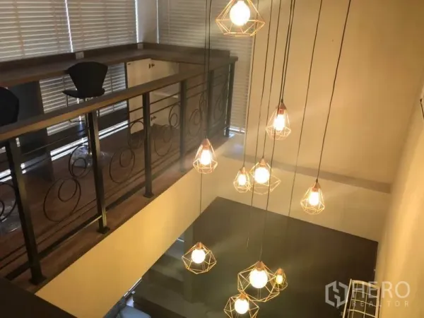 Condominium for sale in Bang Na, Bangkok - Cluster of modern pendant lights hanging in a double-height void beside the mezzanine railing.