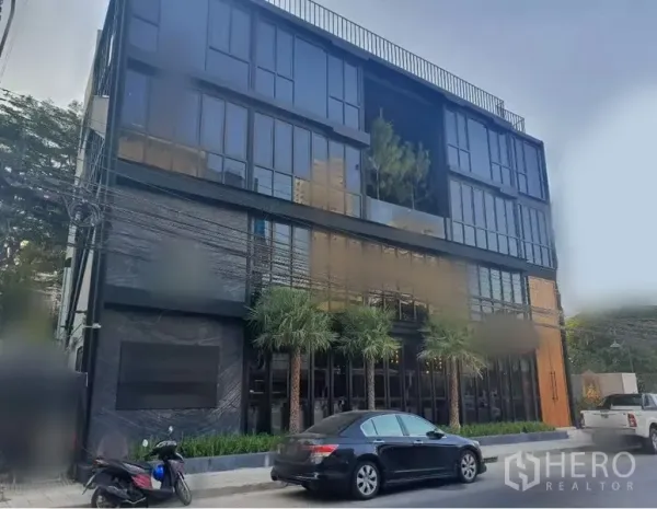 零售空间 出租在Khlong Toei, Bangkok - 现代黑色玻璃商业楼，临街立面与棕榈景观。