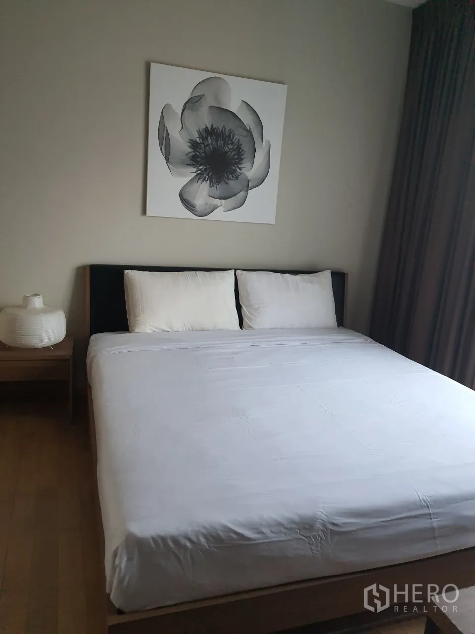 Condominium for rent or sale in Watthana, Bangkok - Master bedroom with a large bed, neutral decor, bedside table and floral wall art.