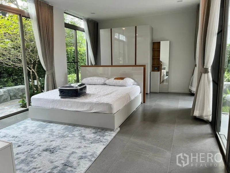 Detached House for rent or sale in Saphan Sung, Bangkok - Master bedroom with wraparound windows, garden views and contemporary furnishings.