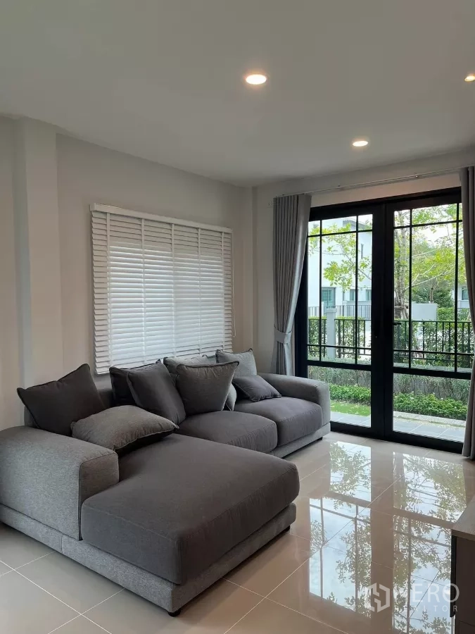 Detached House for rent or sale in Bang Phli, Samut Prakan - Spacious lounge with two sofas, glossy tile floor, and garden views through wide windows.