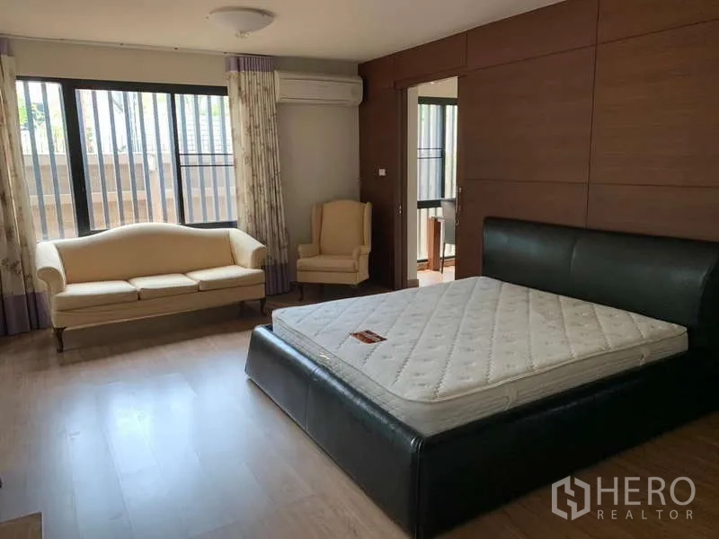 Detached House for rent - Master bedroom with leather bed frame, sofa seating, large windows and wood accent wall.