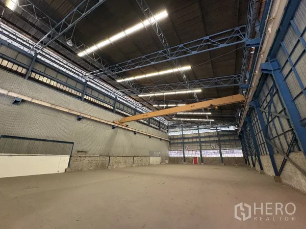 Warehouse for rent in Mueang Samut Prakan, Samut Prakan - High-ceiling warehouse interior with steel trusses and a 5-ton overhead gantry crane.