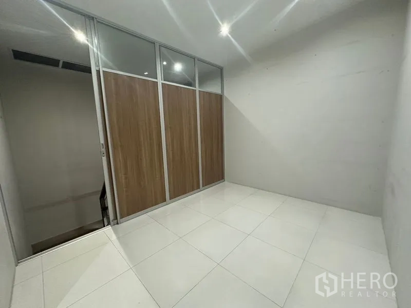 Home Office for rent in Phra Khanong, Bangkok - Small room with sliding glass-and-wood partition and white floor tiles.