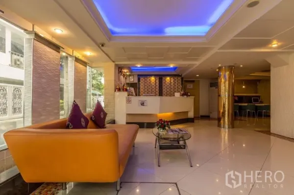 Shophouse for rent or sale in Khlong Toei, Bangkok - Bright lobby with reception desk, orange sofa and blue accent ceiling lights.