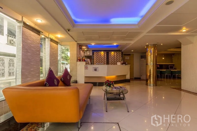 Shophouse for rent or sale in Khlong Toei, Bangkok - Bright lobby with reception desk, orange sofa and blue accent ceiling lights.