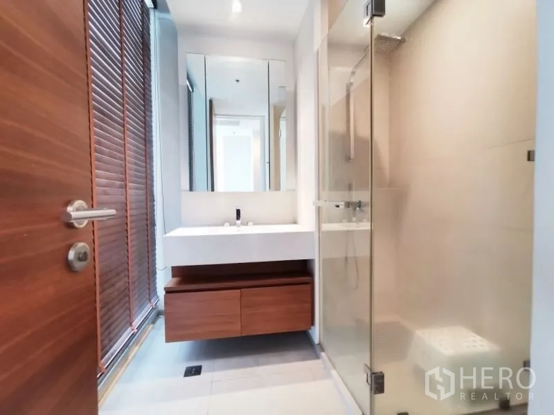 公寓 出租或出售在Khlong San, Bangkok - 明亮卫浴，玻璃淋浴房、大镜面与木质收纳柜。