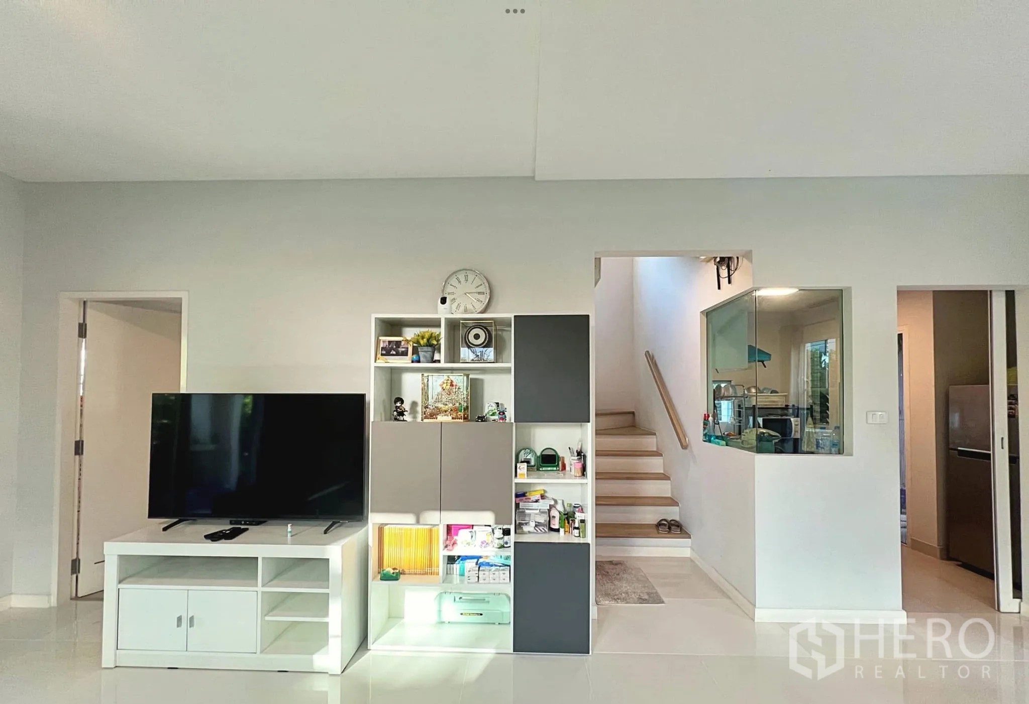 Townhouse for rent or sale in Sai Mai, Bangkok - Media wall with built-in shelves, staircase to upper floor and doorway to kitchen.