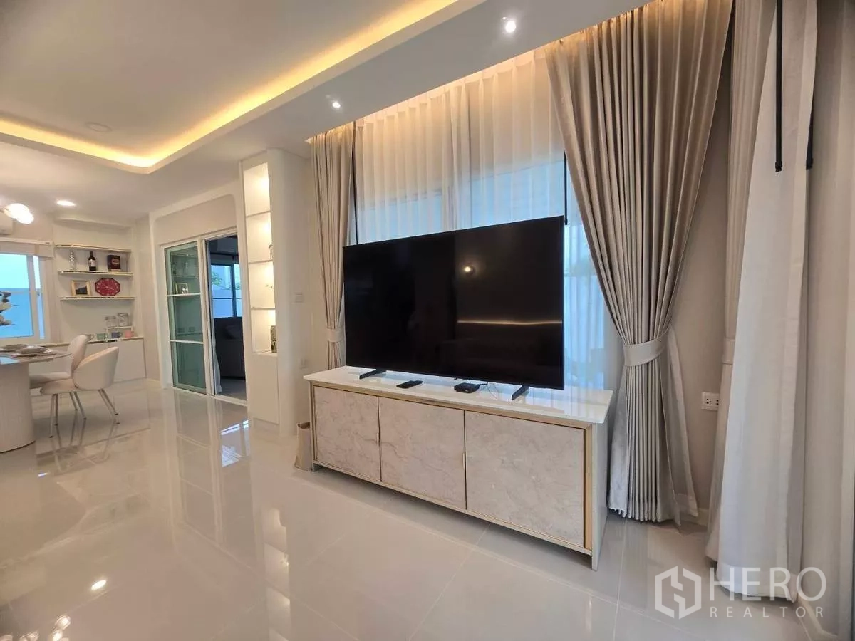 Detached House for rent in Bang Phli, Samut Prakan - Open-plan living and dining area with large TV, recessed lighting and glossy tiled floors.