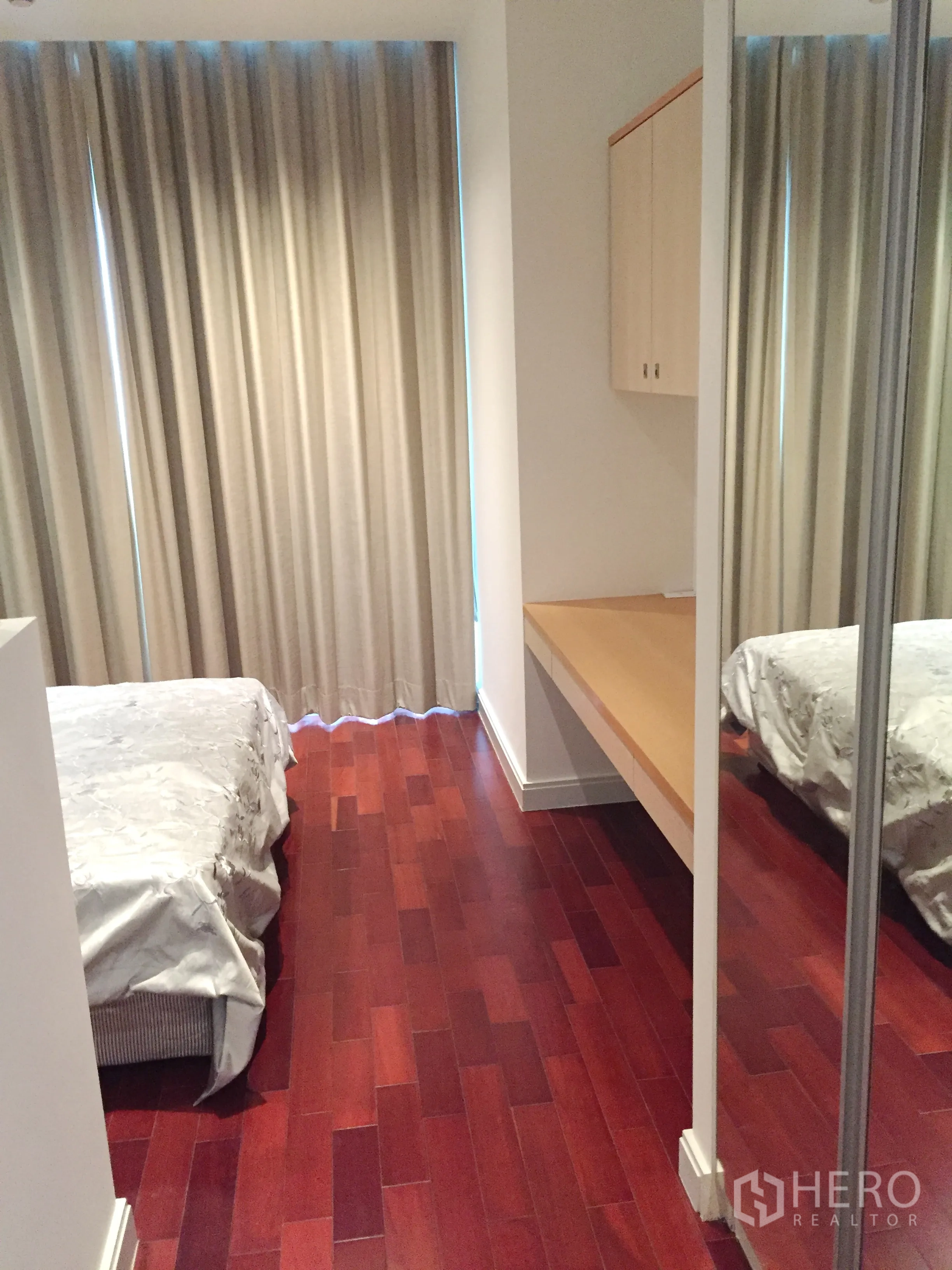 Condominium for rent in Pathum Wan, Bangkok - Second bedroom with mirrored wardrobe, study desk and polished wooden flooring.