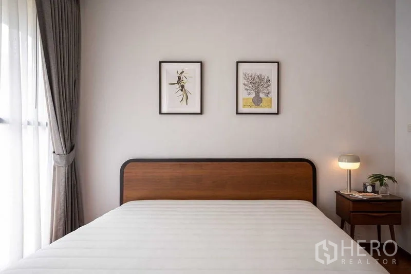 คอนโด ให้เช่าหรือขายในPathum Wan, Bangkok - ภาพระยะใกล้หัวเตียงไม้ พร้อมโคมไฟข้างเตียงและรูปติดผนัง