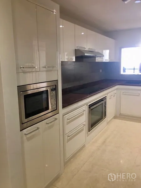 คอนโด ให้เช่า - ผนังเครื่องใช้ในครัว มีไมโครเวฟ เตาอบ และตู้เงามัน