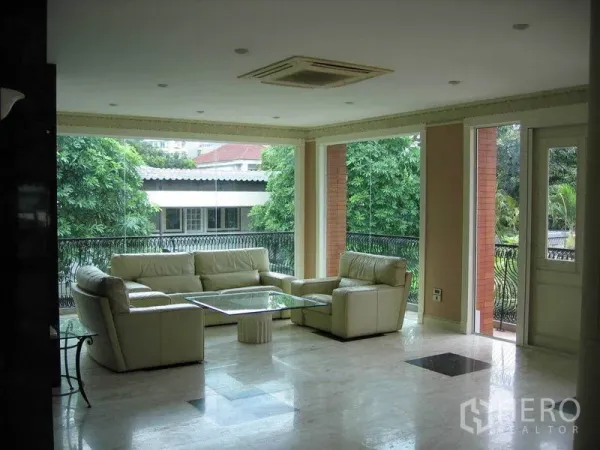 บ้าน ให้เช่าในWatthana, Bangkok - ห้องนั่งเล่นสว่างพื้นหินอ่อน โซฟาหนังสีครีม หน้าต่างบานใหญ่เปิดสู่ระเบียงชมสวน