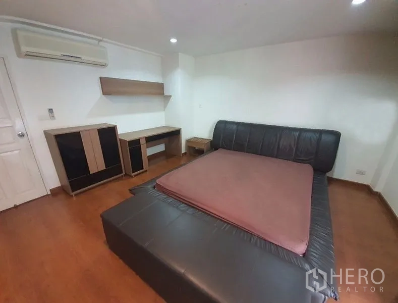 Townhouse for rent in Phaya Thai, Bangkok - Bedroom with leather platform bed, built-in desk and shelves, wood flooring and air conditioner.