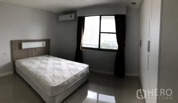 公寓 出租在Watthana, Bangkok - 通透明亮卧室，双人床、嵌入式衣柜、空调与城市景观窗。