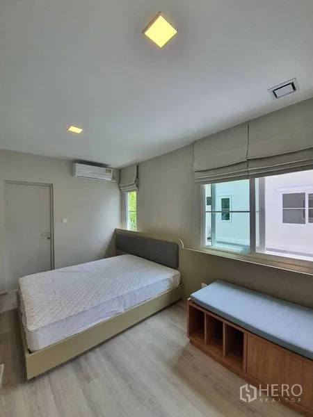 Townhouse for rent - Second bedroom with bed, window seat, and wall-mounted air conditioner.