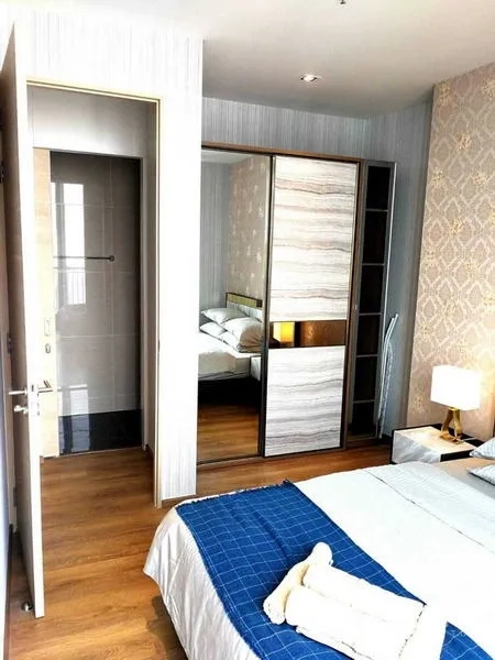 คอนโด ให้เช่า - ห้องนอนมาสเตอร์พร้อมตู้เสื้อผ้าบานเลื่อน โคมไฟหัวเตียง และทางเข้าห้องน้ำ