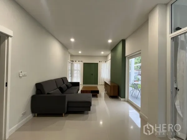 Detached House for rent in Saphan Sung, Bangkok - Long living area facing the patio with green feature door and wooden console.
