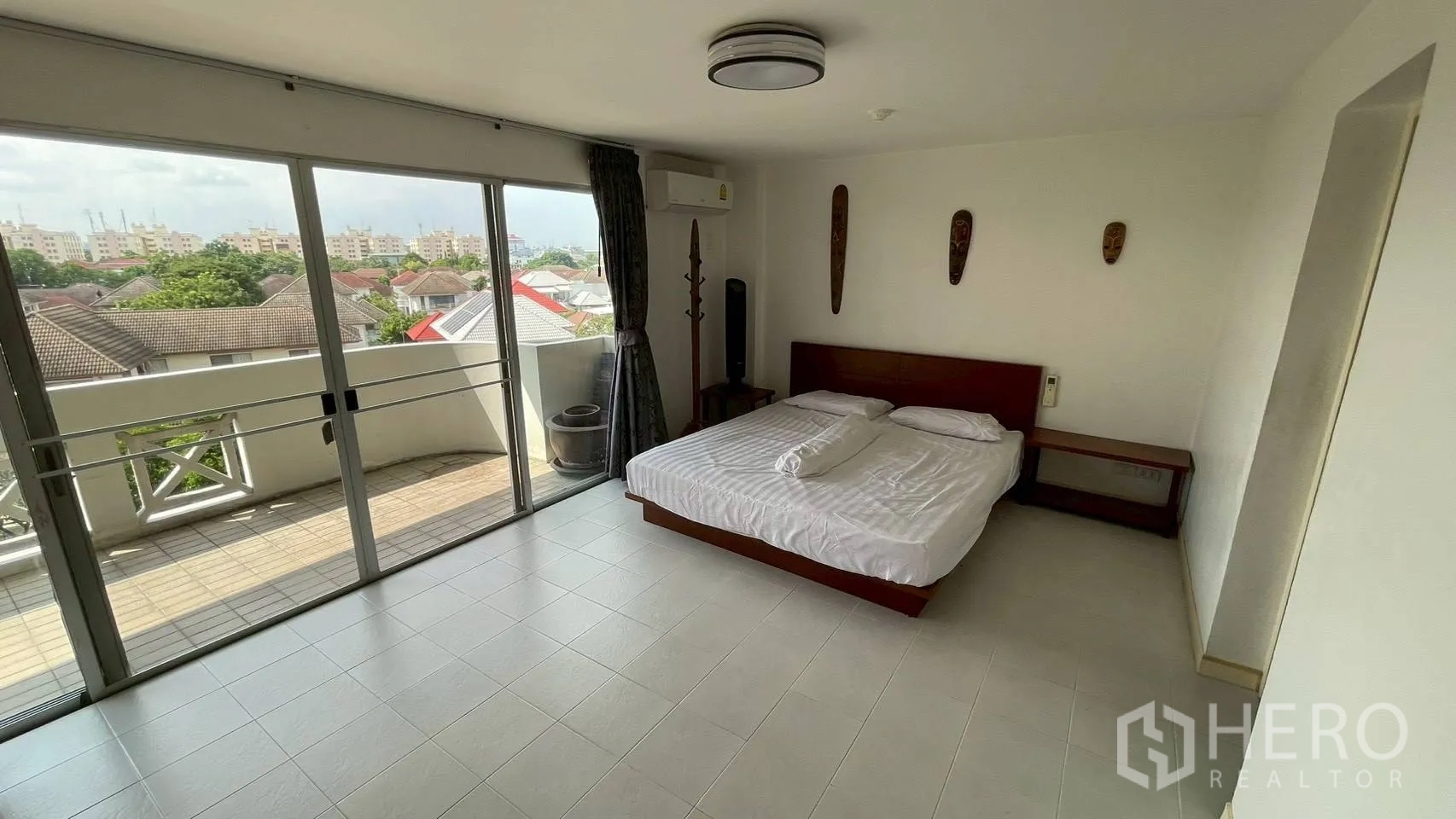 Condominium for sale in Wang Thonglang, Bangkok - Master bedroom opening to a balcony with city and rooftop views.
