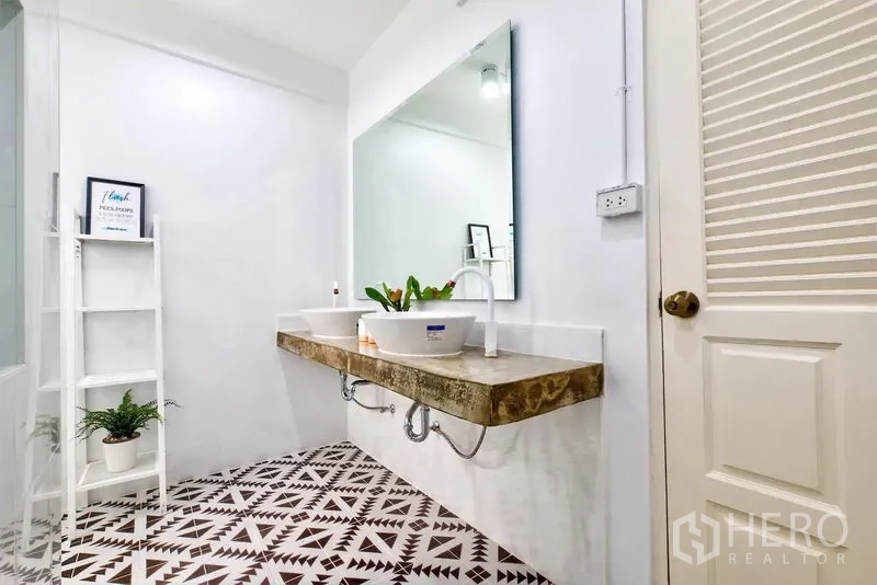 Townhouse for rent in Bang Rak, Bangkok - Bathroom with patterned floor tiles, double vessel sinks, and a large mirror.