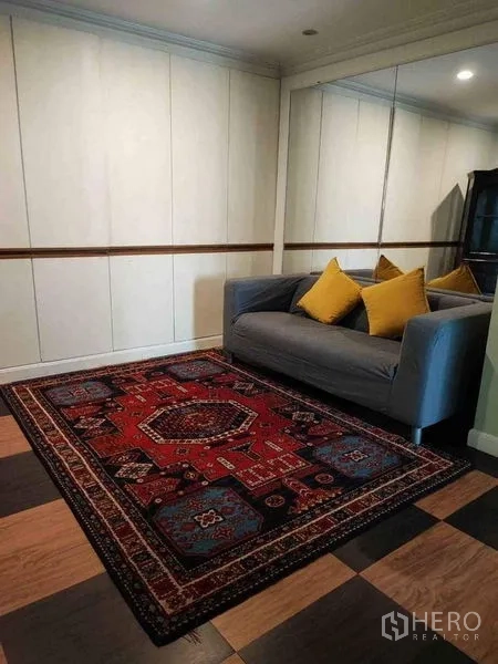 คอนโด ให้เช่าหรือขายในWatthana, Bangkok - มุมพักผ่อนพร้อมโซฟาสีเทา หมอนสีเหลือง และพรมลายแดง