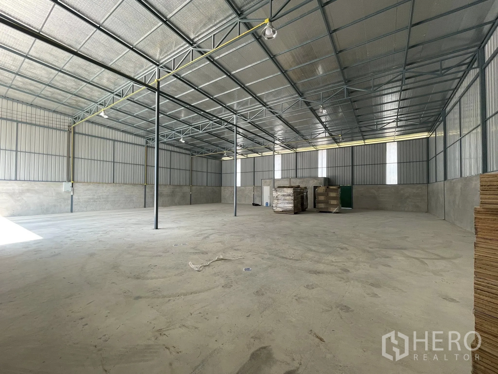 Warehouse for rent in Bang Phli, Samut Prakan - Open-plan warehouse interior with steel truss roof, lighting, and concrete floor.