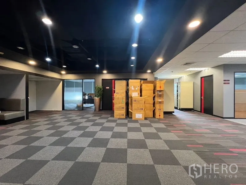 办公空间 出租在Huai Khwang, Bangkok - 宽敞开放式办公室，方格地毯与堆放纸箱，顶置筒灯照明。