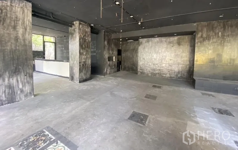 零售空间 出租在Khlong Toei, Bangkok - 待装修的店铺内部，多根立柱与灰色地面。