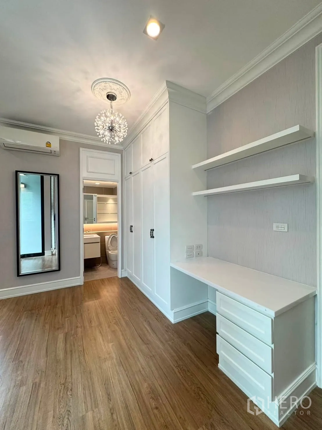 Townhouse for rent in Lat Phrao, Bangkok - Bedroom with chandelier, built-in wardrobe and desk, connected to an ensuite.