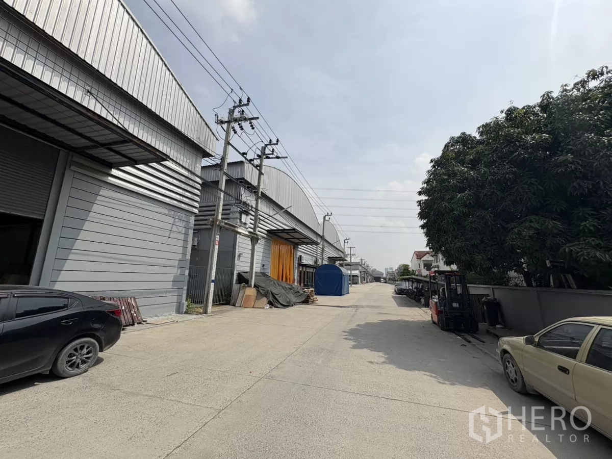 Warehouse for rent in Bang Phli, Samut Prakan - Internal road of industrial compound lined with metal warehouses and power poles.
