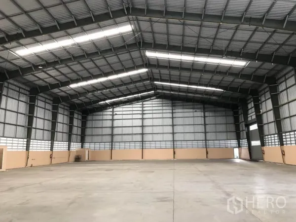 Warehouse for rent in Pathum Thani - Open warehouse space with tall columns, bright strip lighting and a wide clear floor area.