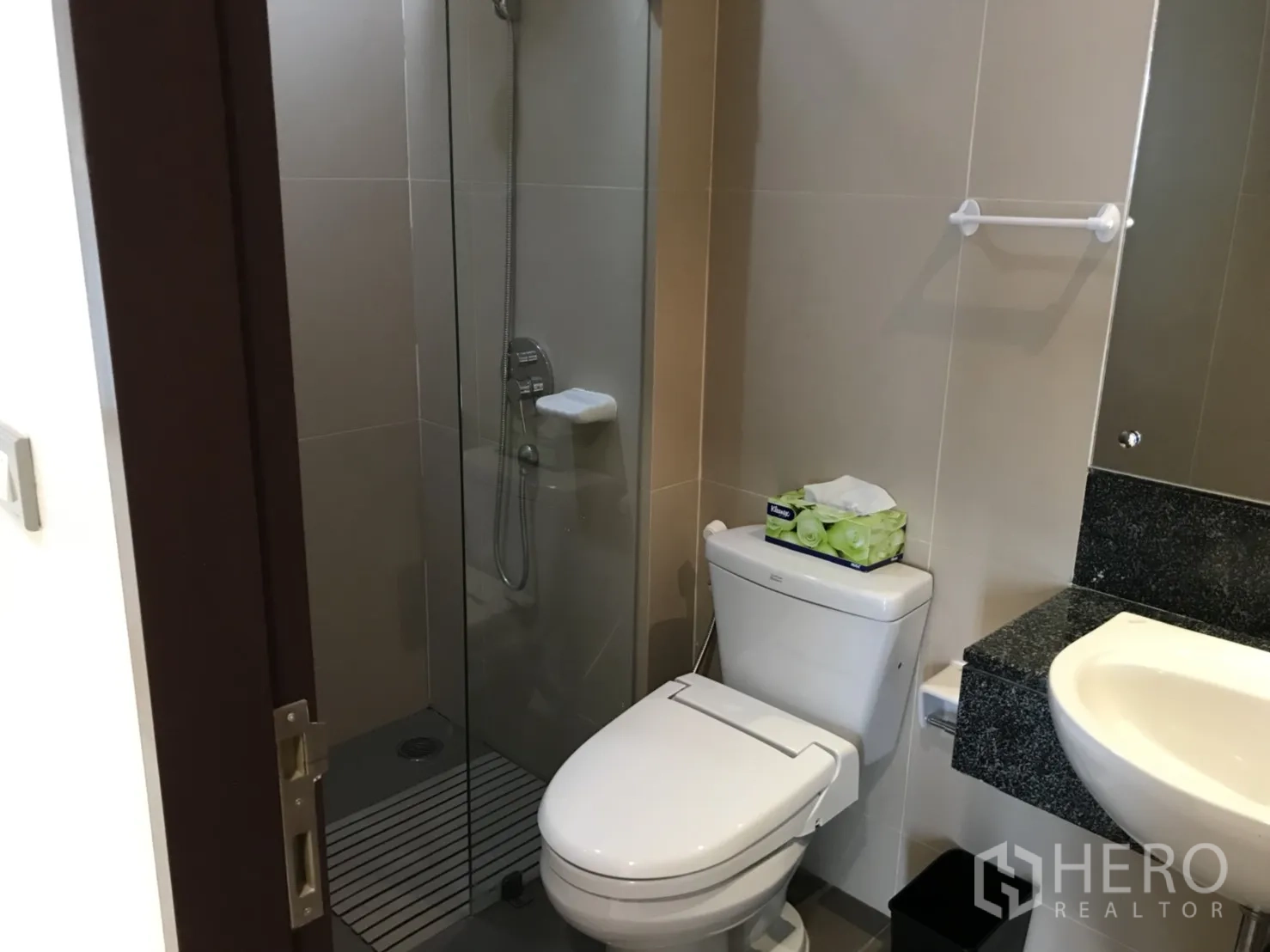 Condominium for rent in Watthana, Bangkok - Modern bathroom with glass-enclosed shower, toilet, and countertop basin.
