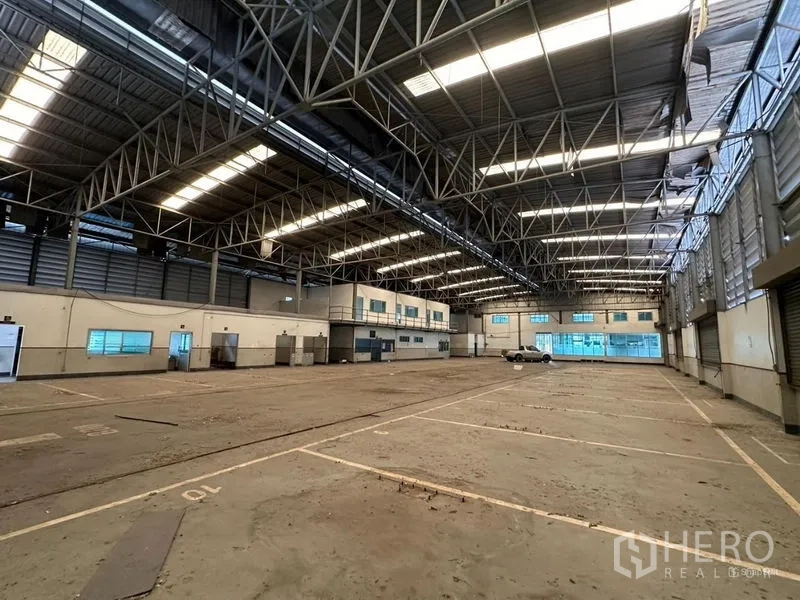 Showroom for rent or sale in Lam Luk Ka, Pathum Thani - Expansive factory floor with skylights and office pods.