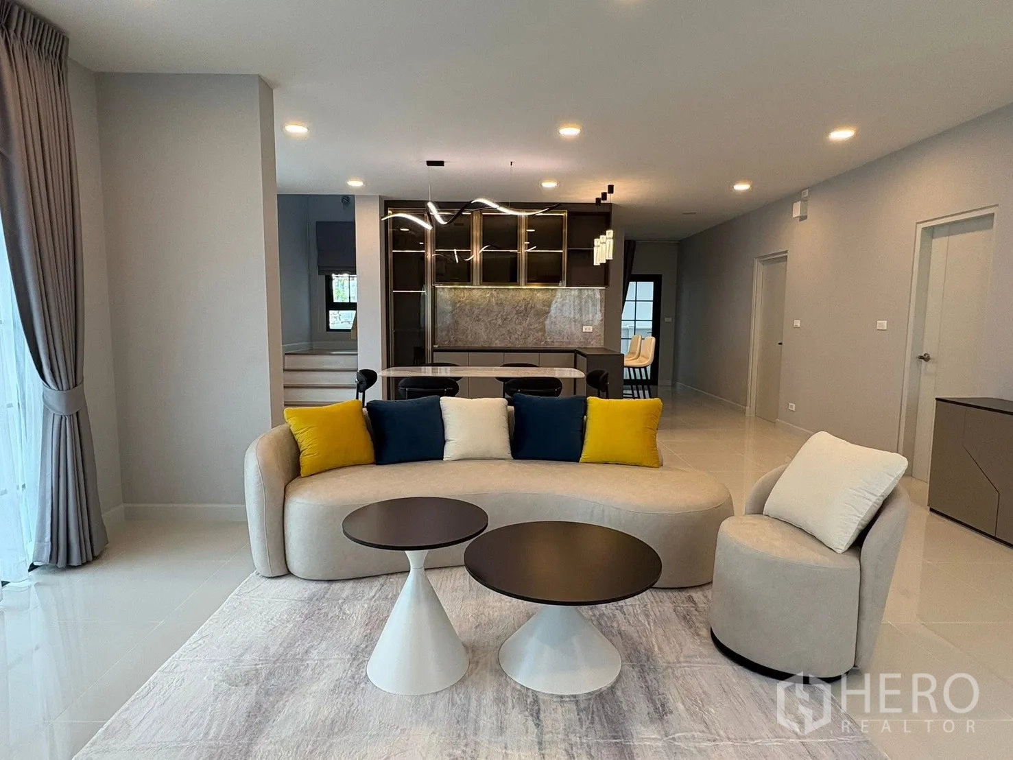 Detached House for rent in Bang Phli, Samut Prakan - Open-plan living room with curved sofa, lounge chair and round coffee tables facing the dining zone.