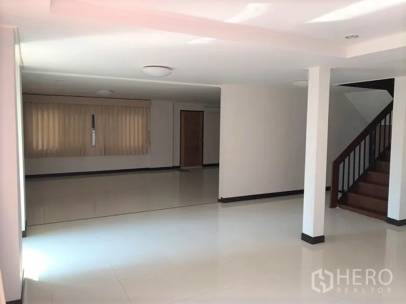 Detached House for rent in Suan Luang, Bangkok - Spacious open-plan living area with white tile floors, columns and wooden staircase