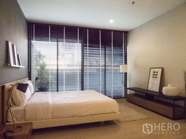 Condominium for rent or sale in Watthana, Bangkok - Spacious bedroom with large windows, blackout blinds and minimalist furniture.