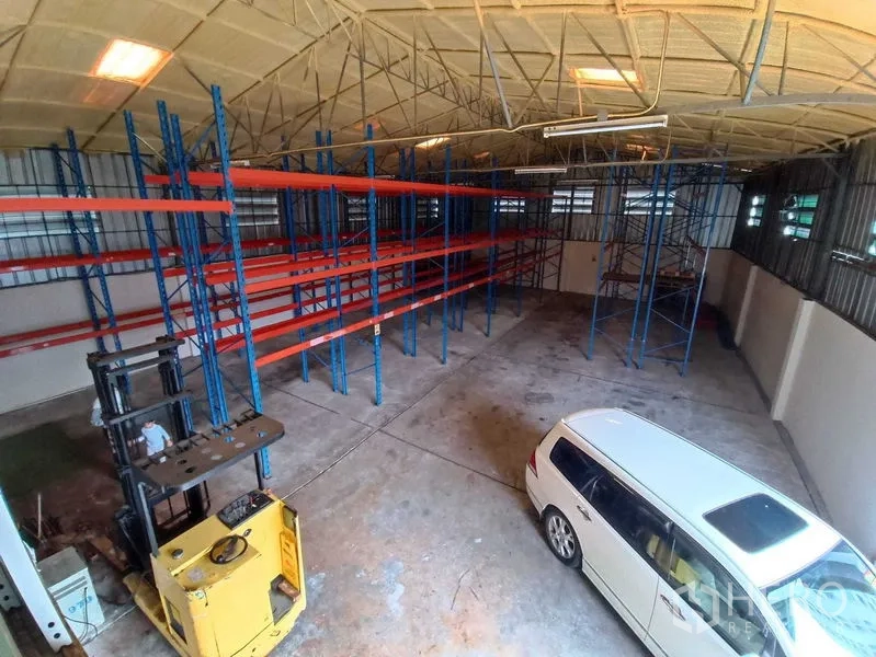 Warehouse for rent in Suan Luang, Bangkok - Elevated view of the warehouse showing racks, a forklift, and a white car.