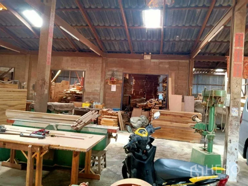 บ้าน ขายในBang Na, Bangkok - เวิร์กชอปโปร่ง มีไม้ เครื่องจักร และรถสกู๊ตเตอร์ใต้หลังคาสูง