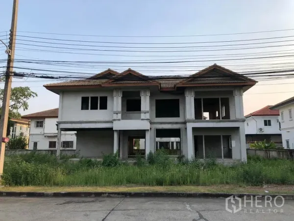 บ้าน ขายในLam Luk Ka, Pathum Thani - ด้านหน้าบ้านเดี่ยวสองชั้นก่อสร้างไม่เสร็จ หลังคากระเบื้อง สนามหญ้ารก ในลำลูกกา ปทุมธานี