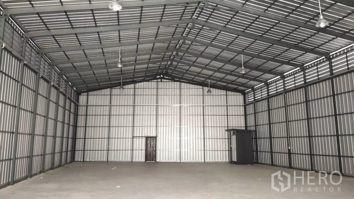 Warehouse for rent in Bang Lamung, Chon Buri - Empty storage bay showing gabled roof, ventilation louvers and back wall access door.