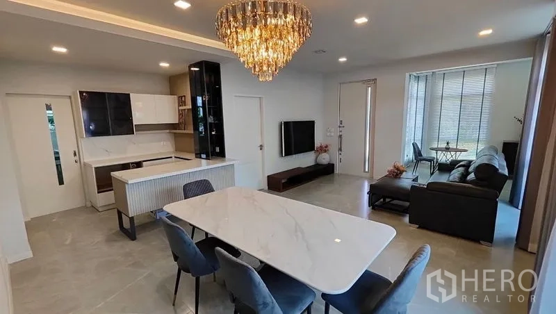 บ้าน ให้เช่าในPrawet, Bangkok - พื้นที่นั่งเล่น–รับประทานอาหารโถงกว้าง มีโคมแชนเดอเลียร์ ทีวีวอลล์ และครัวไอซ์แลนด์