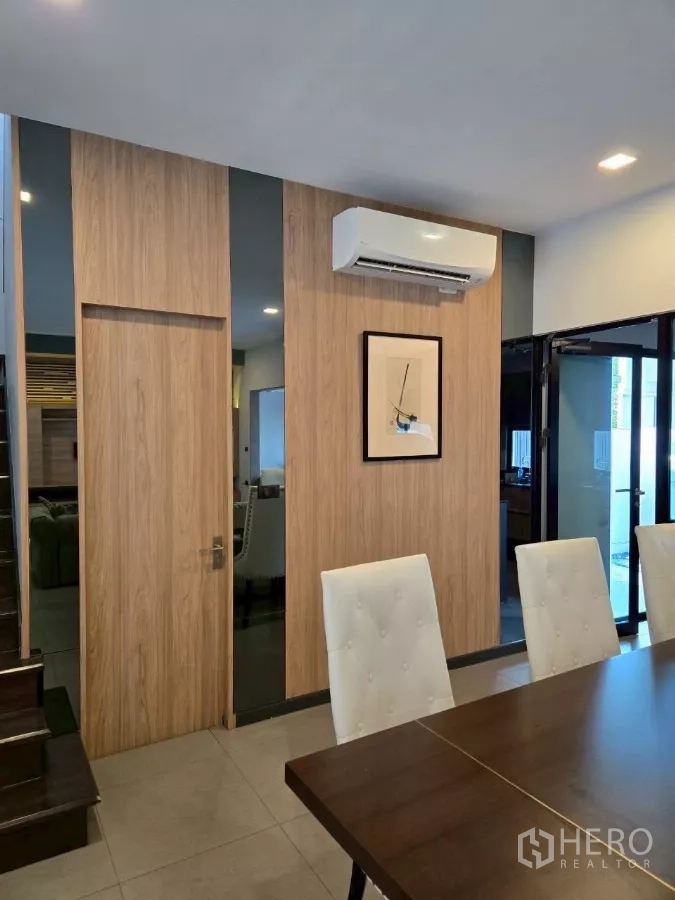 Townhouse for rent in Bang Phli, Samut Prakan - Close-up of dining area featuring a wood accent wall, wall-mounted air conditioner, and sliding door.