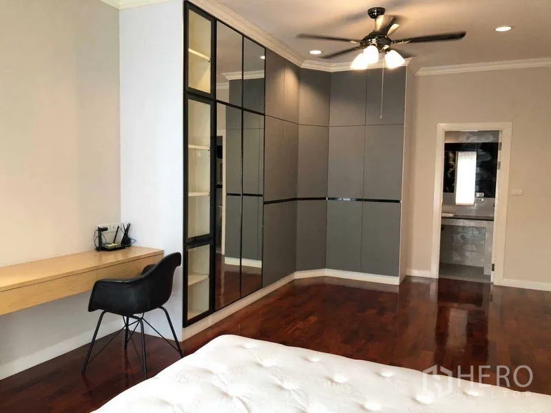 独立式住宅 出租在Bang Na, Bangkok - 卧室内镜面衣柜、书桌、吊扇及套内门。