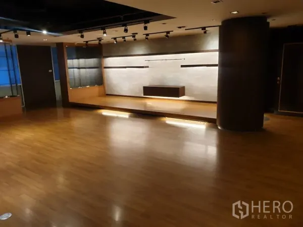 Office Space for rent - Large multipurpose room with wood floors, a raised platform and track lighting.