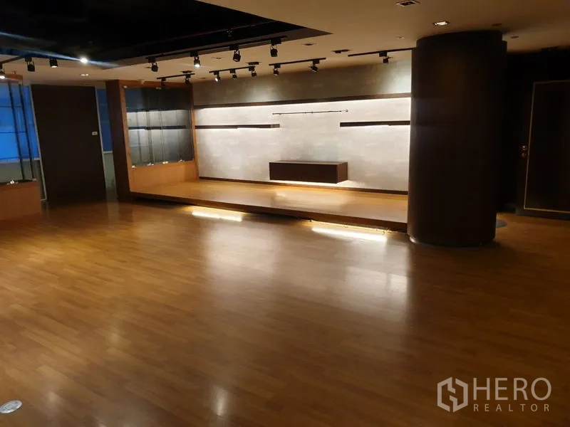 Office Space for rent - Large multipurpose room with wood floors, a raised platform and track lighting.