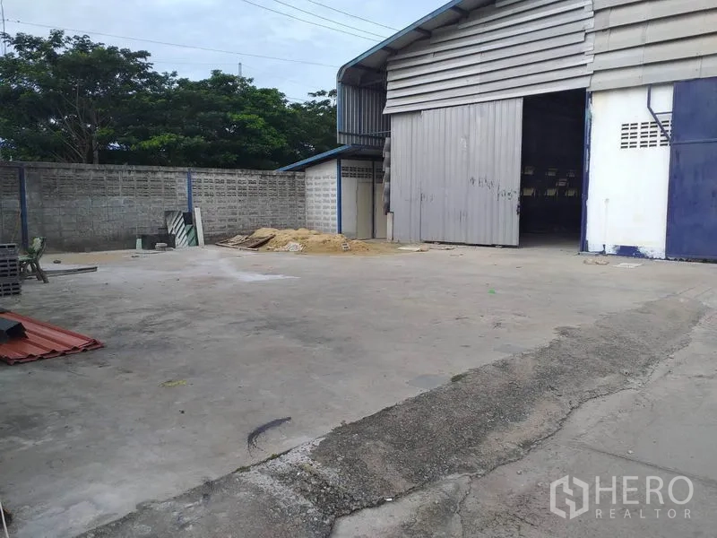 Warehouse for rent in Pak Kret, Nonthaburi - Side view of warehouse with large rolling door and paved yard suitable for trucks.