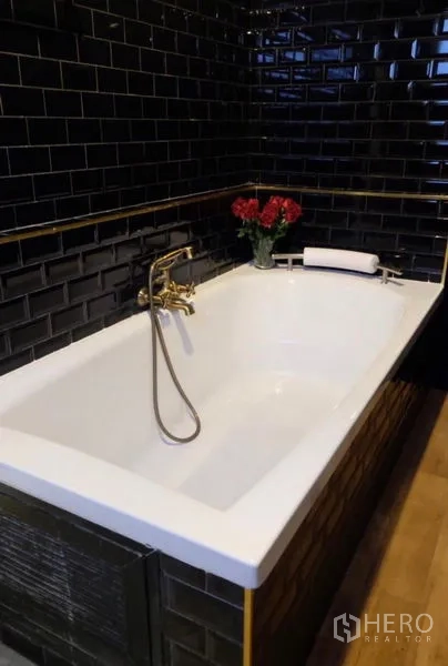 Detached House for rent in Suan Luang, Bangkok - Rectangular soaking bathtub surrounded by black subway tiles and a brass hand shower.