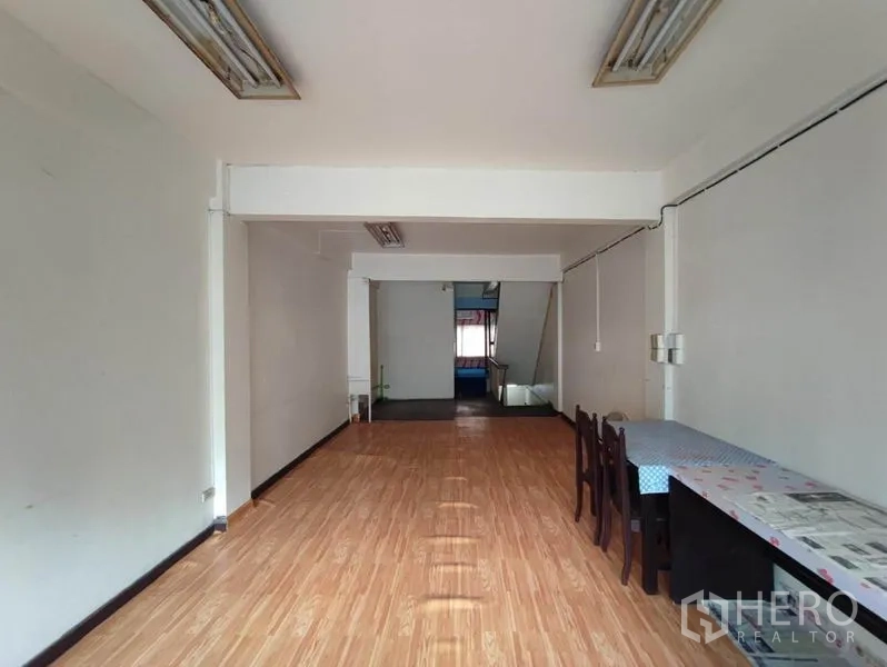 Shophouse for rent in Khlong Toei, Bangkok - Open-plan room with white walls, wood-look flooring and fluorescent lighting.